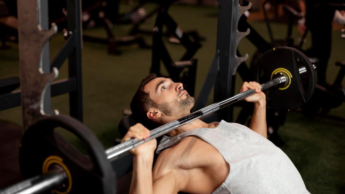 Un joven, levantando peso en el gimnasio.