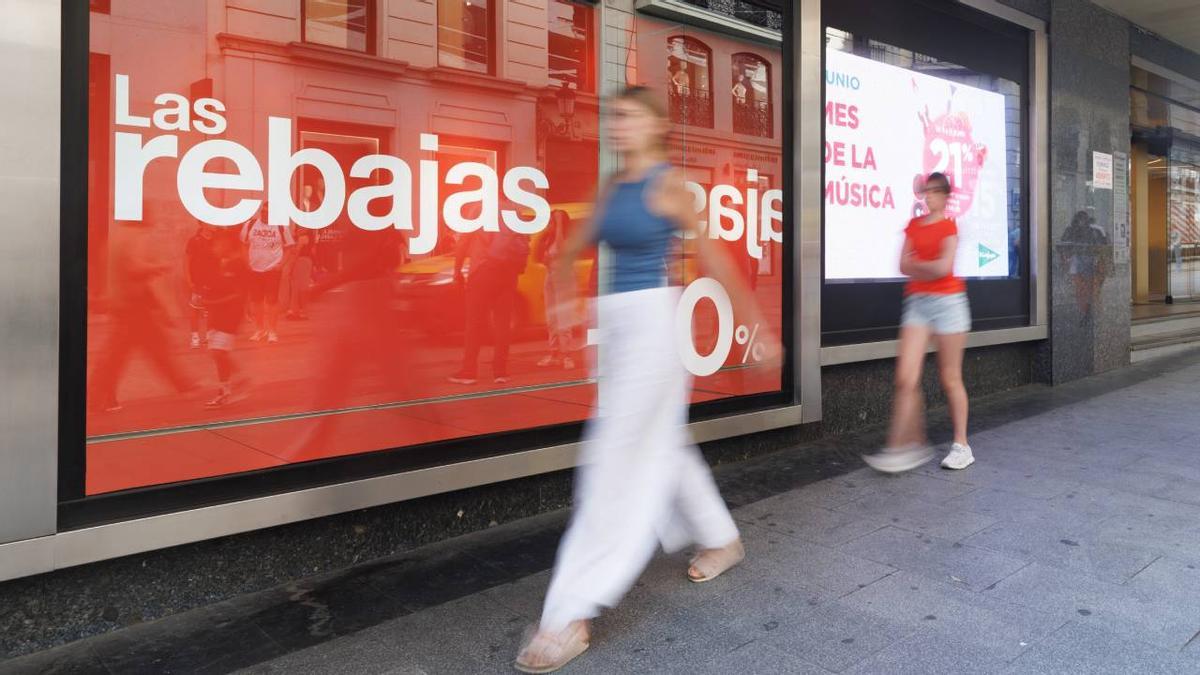 Una mujer pasea junto a un anuncio de rebajas