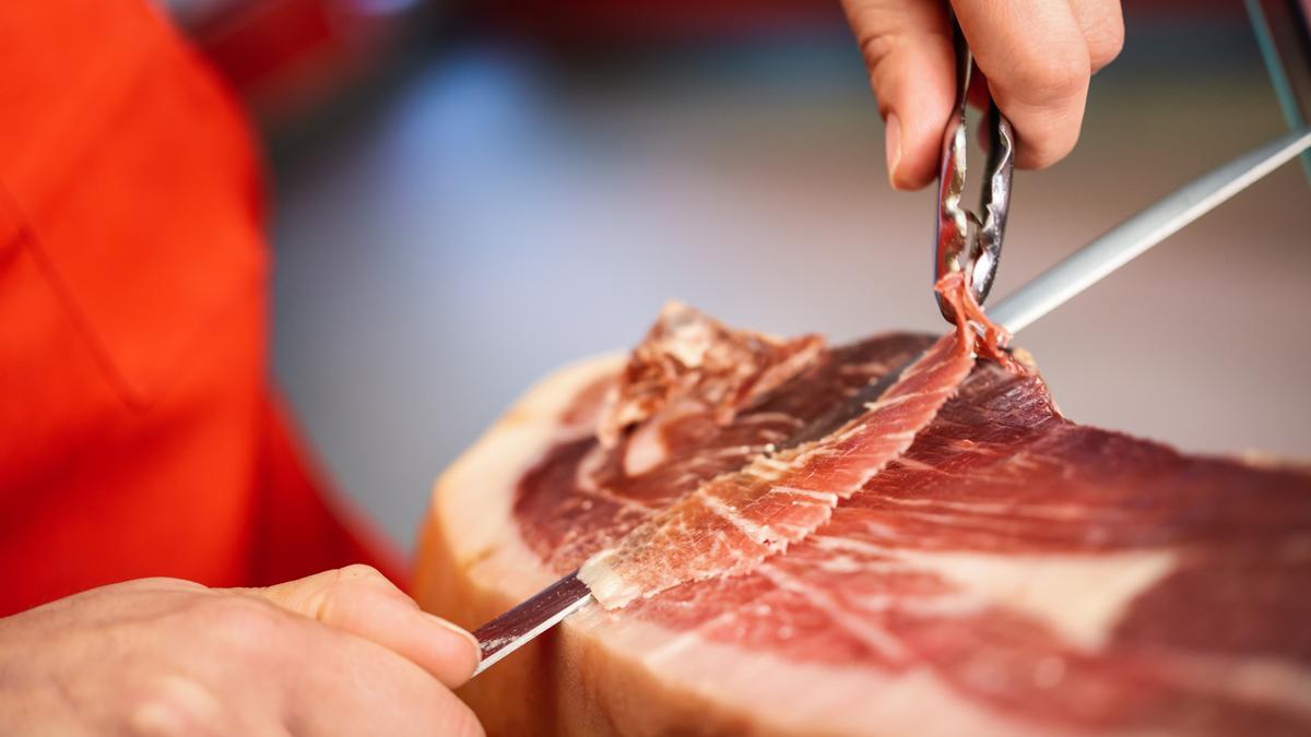 Un cortador profesional extrae jamón de una paleta.