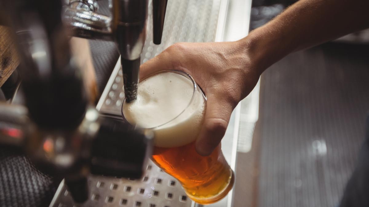 UN camarero sirve un vaso de cerveza de barril.