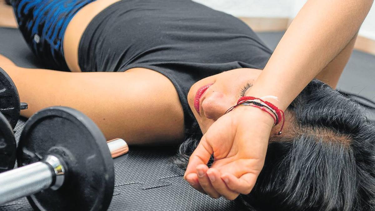 Una mujer presenta síntomas de fatiga y cansancio durante una sesión de entrenamiento.