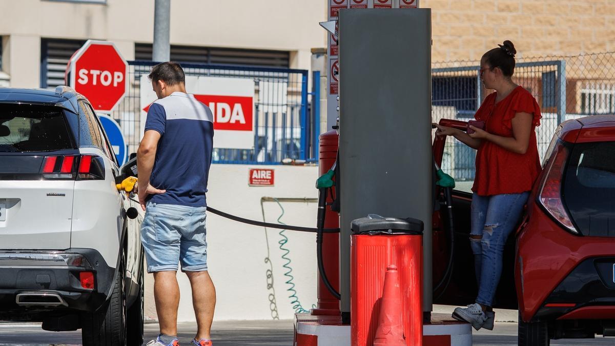 Dos personas echan gasolina a su vehículo en una estación de servicio.