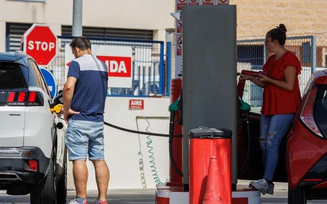 Dos personas echan gasolina a su vehículo en una estación de servicio. Dos personas echan gasolina a su vehículo en una estación de servicio.