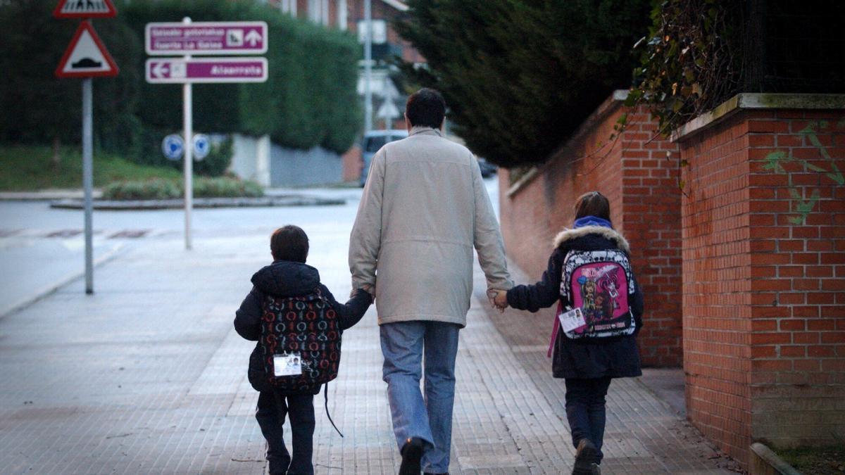 Un padre acompañando a sus hijos al colegio.