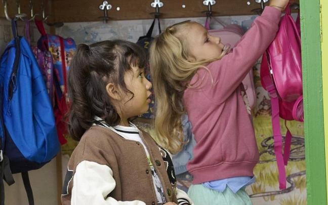 Dos niñas cuelgan sus mochilas en el armario en el día de la vuelta al cole en San Juan de la Cadena, en Pamplona. Dos niñas cuelgan sus mochilas en el armario en el día de la vuelta al cole en San Juan de la Cadena, en Pamplona.