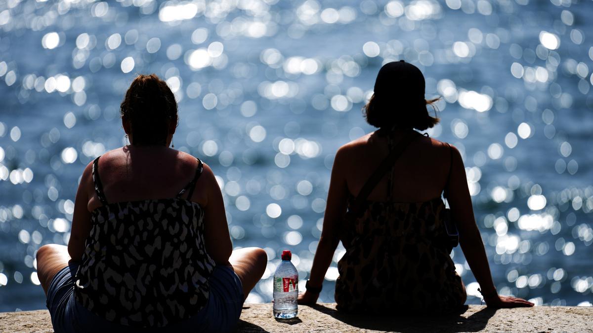 Dos mujeres junto al mar comparten una botella de agua