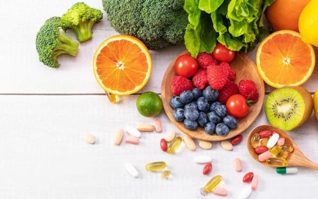 Frutas y verduras frescas junto a un puñado de medicamentos.