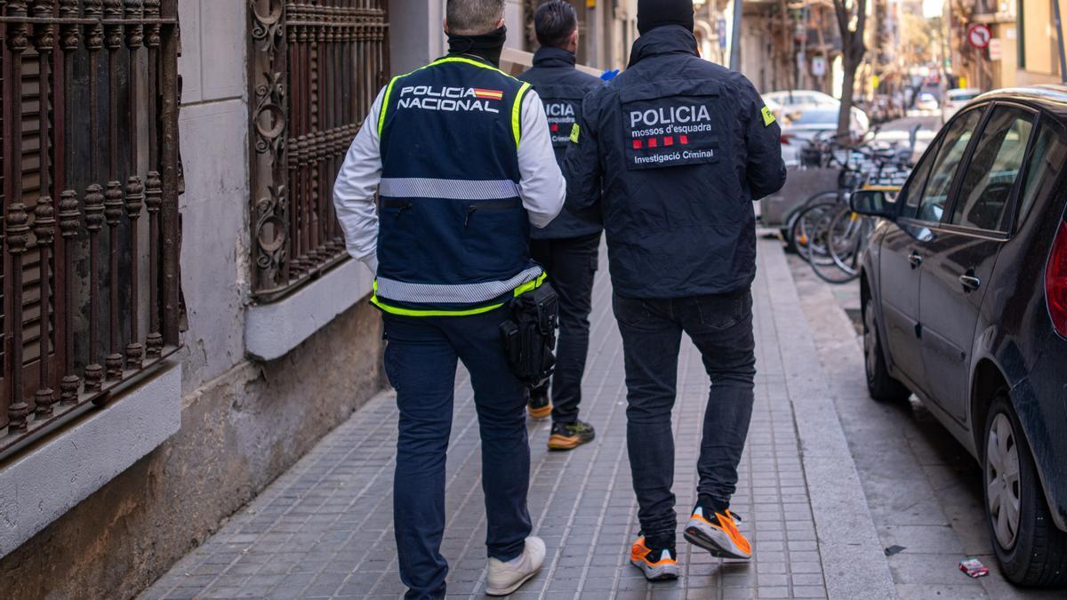 Un agente de los Mossos d'Esquadra y otro de la Policía Nacional durante un operativo policial.