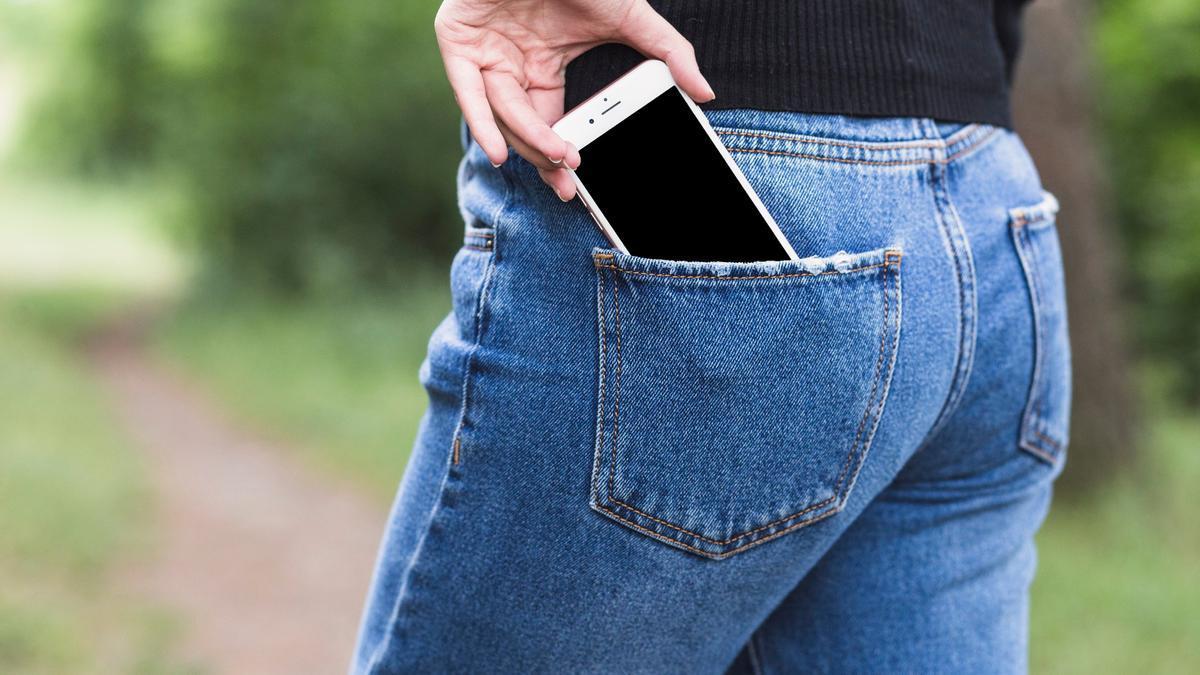 Una mujer guarda el móvil en el bolsillo trasero del pantalón.