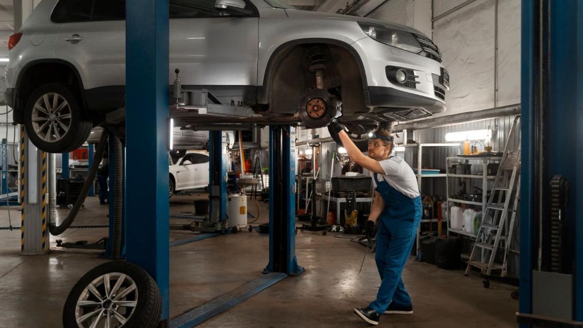 Un mecánico, reparando un coche en un taller.