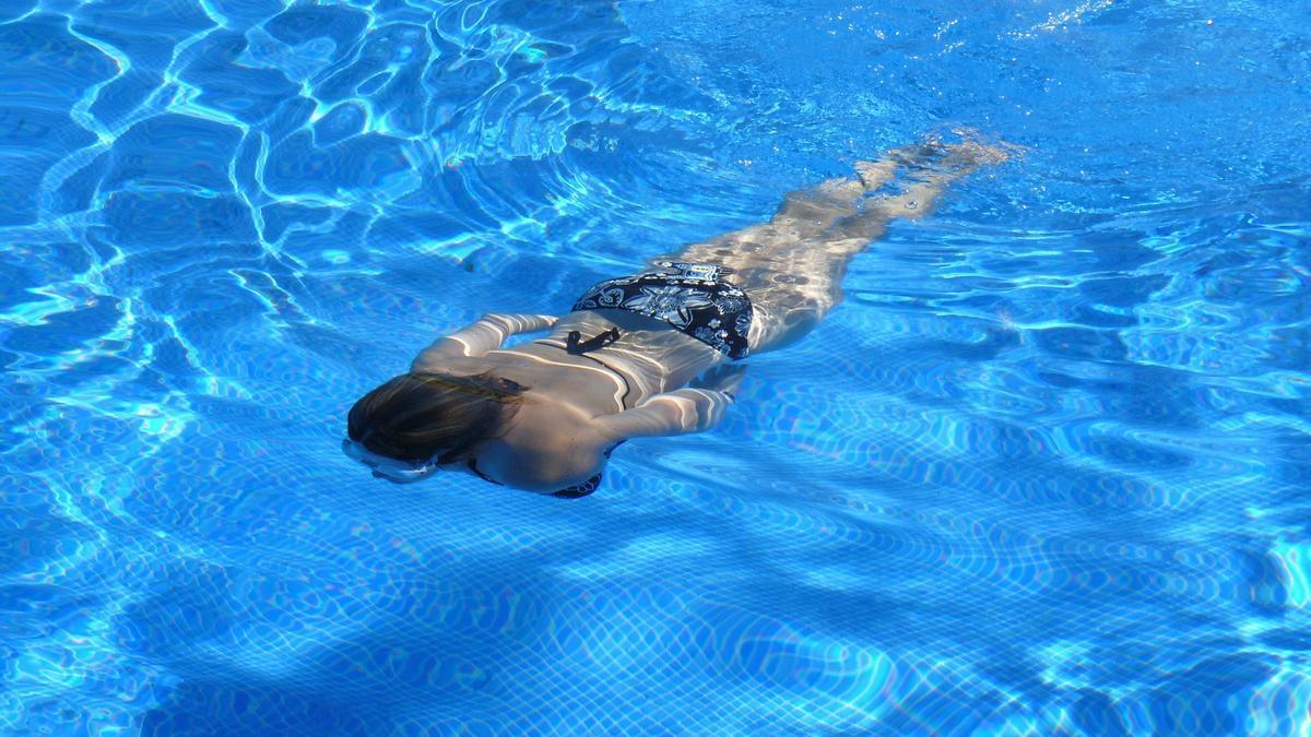 Una mujer nada en una piscina.