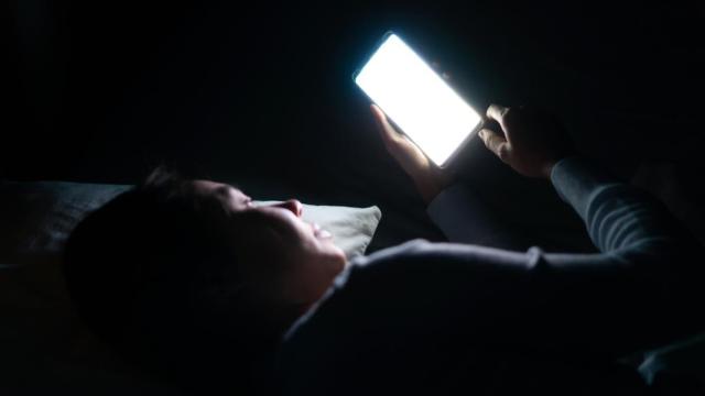 Mujer usa el móvil de noche.