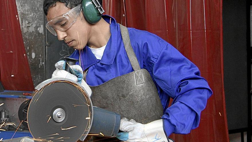 Un joven trabaja en una máquina industrial, uno de los sectores que demandan más mano de obra.