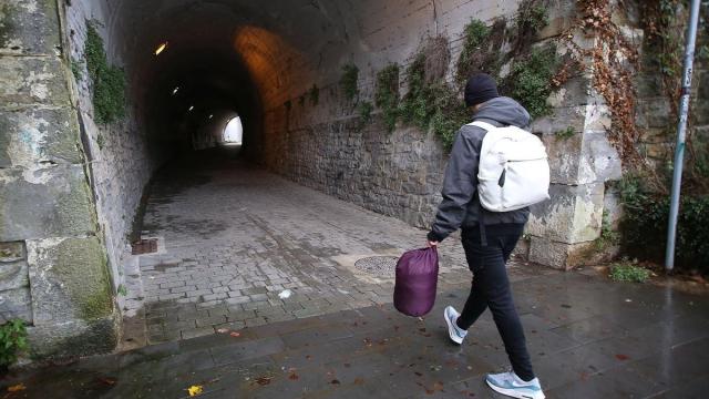 Joven inmigrante caminando hacia el túnel en el que suele pasar la noche.