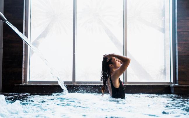 Una mujer se relaja mientras toma un baño en la piscina de un spa.