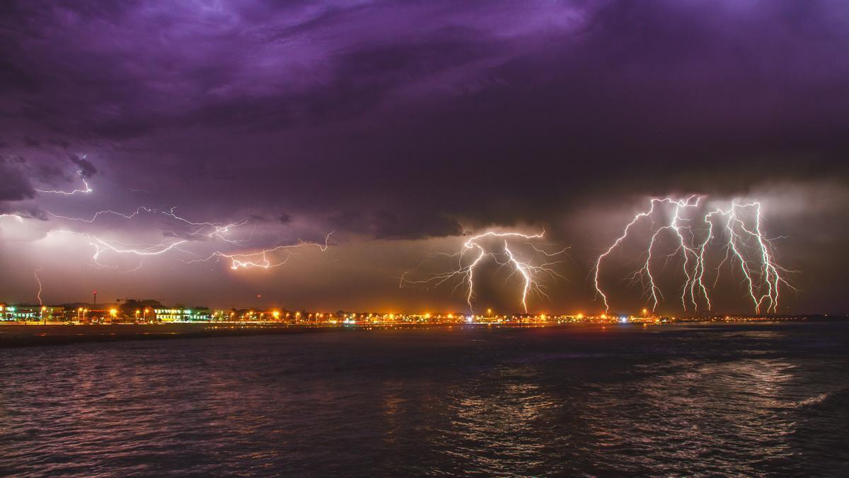 Numerosos rayos descargan sobre una ciudad durante una fuerte tormenta.