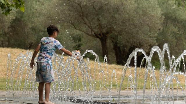 Un niño se refresca en una fuente durante una ola de calor.