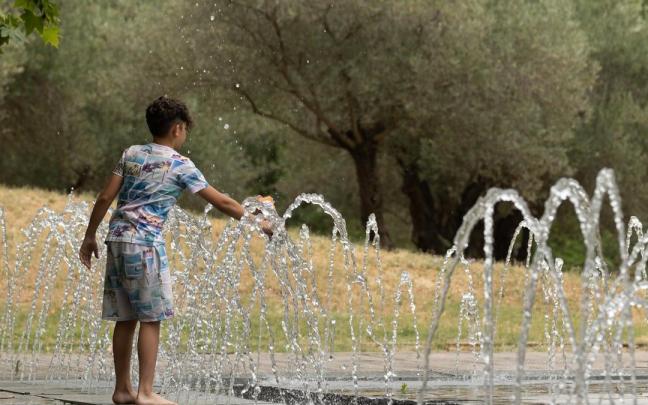 Un niño se refresca en una fuente durante una ola de calor.