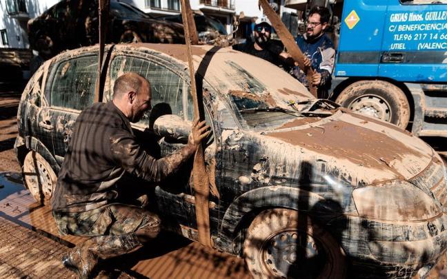 Un hombre saca un vehículo dañado por la DANA con una grúa en Utiel