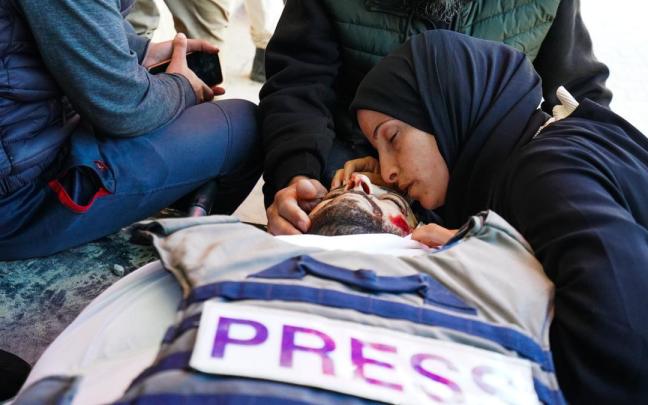 Una mujer reza junto al cadáver del periodista, Mohamed Wishah, asesinado por Israel en Gaza.