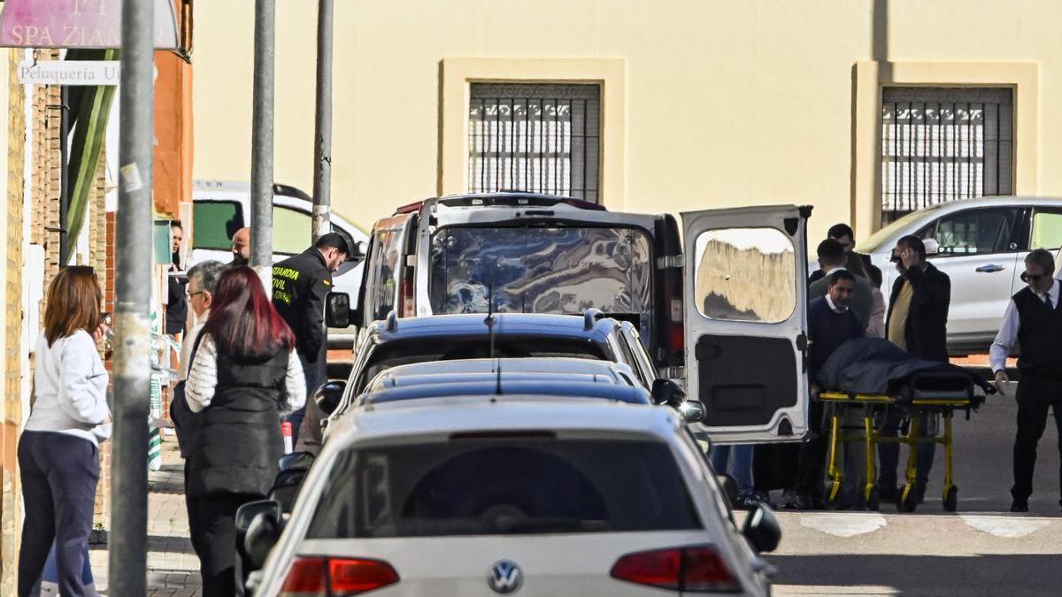 Empleados de la funeraria trasladan el cuerpo sin vida de una mujer de una vivienda de la localidad sevillana de Brenes.