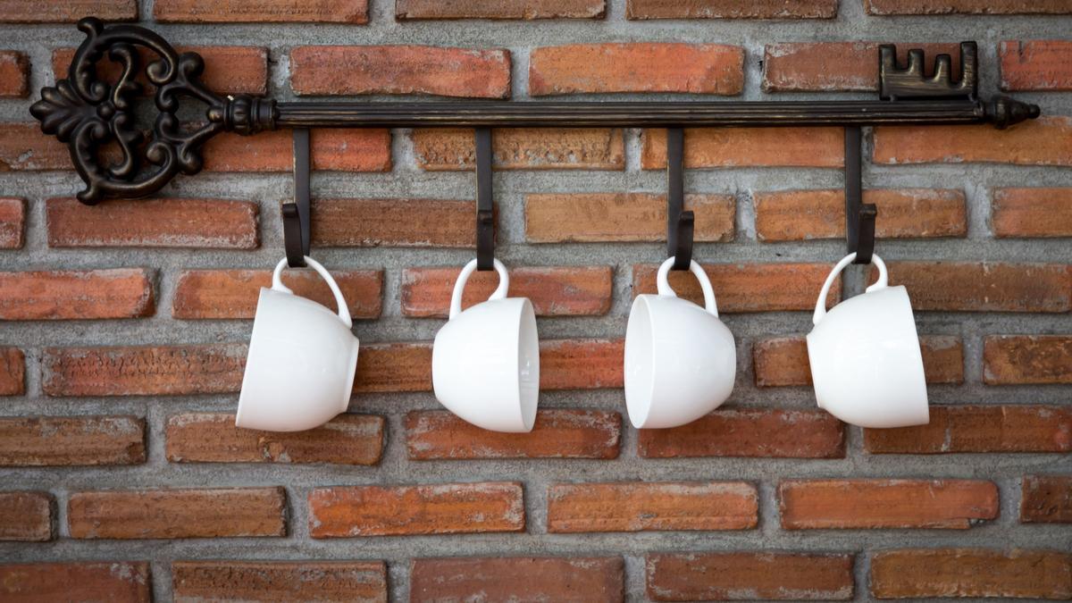 Tazas blancas de porcelana cuelgan en una cocina.