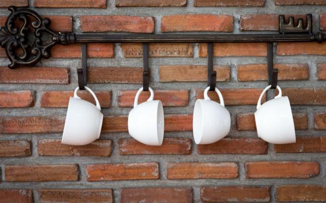 Tazas blancas de porcelana cuelgan en una cocina.