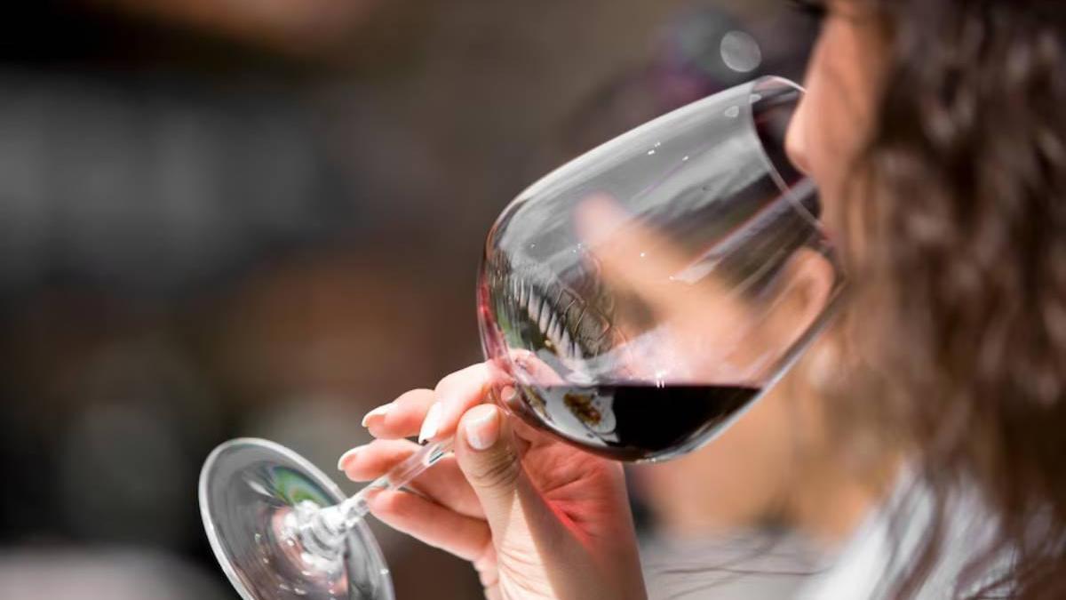 Primer plano de una mujer bebiendo una copa de vino tinto.