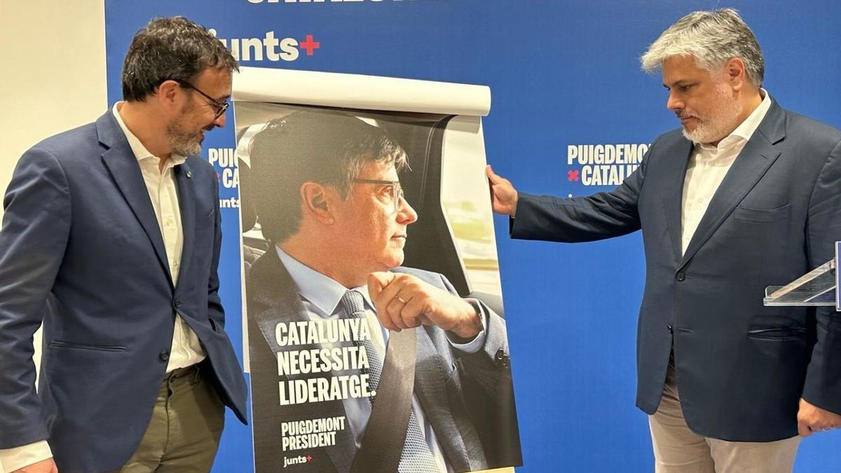 Josep Rius y Albert Batet enseñan el cartel electoral de Puigdemont.