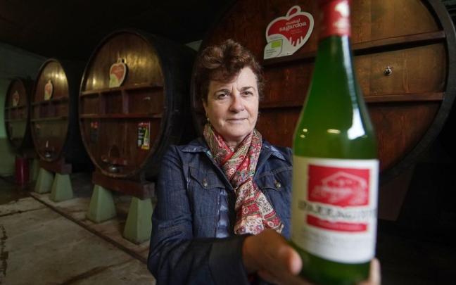 Arantza Eguzkiza entre las kupelas de casa, mostrando una sidra lista para deleitar a los paladares.