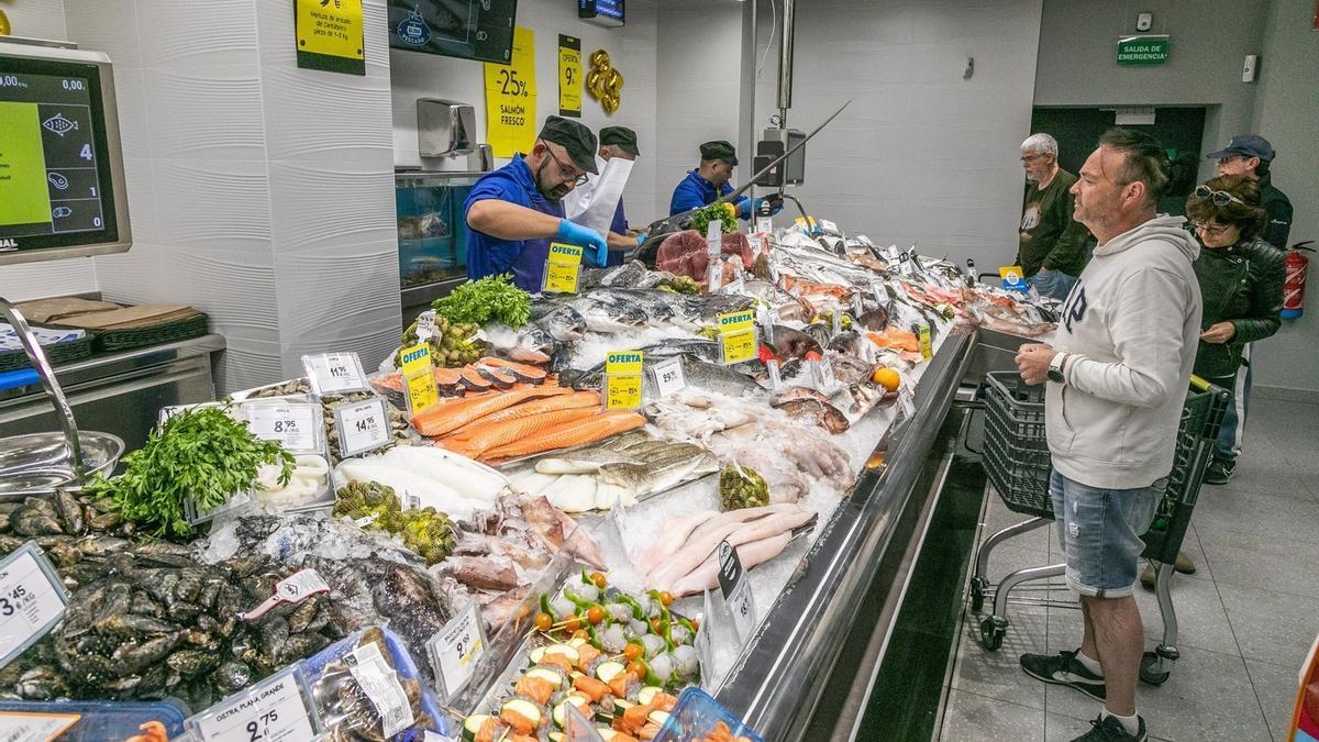 Un grupo de personas esperan cola para comprar pescado.