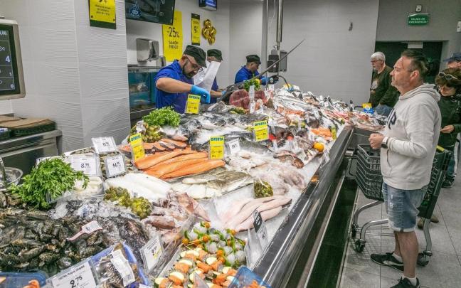 Un grupo de personas esperan cola para comprar pescado.