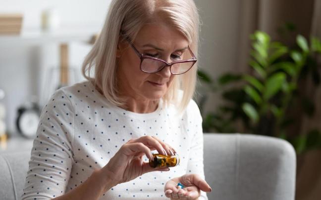 Una mujer toma un suplemento durante la menopausia.