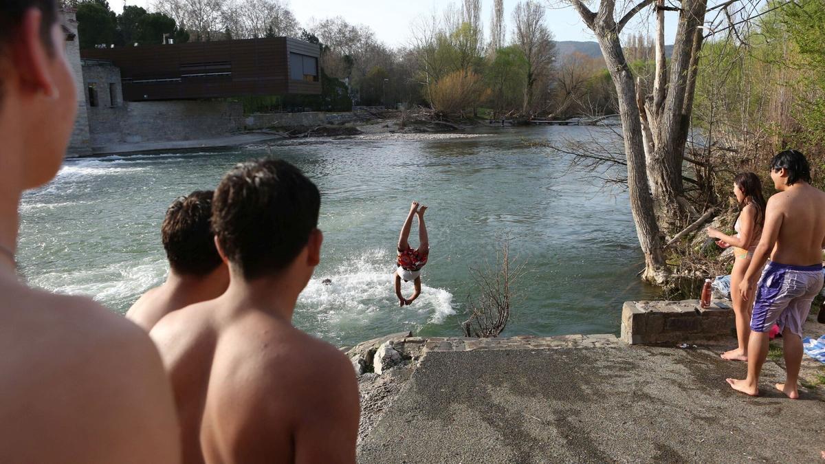 Un grupo de jóvenes se baña en el río Arga el último día del invierno de 2024 debido a las altas temperaturas.