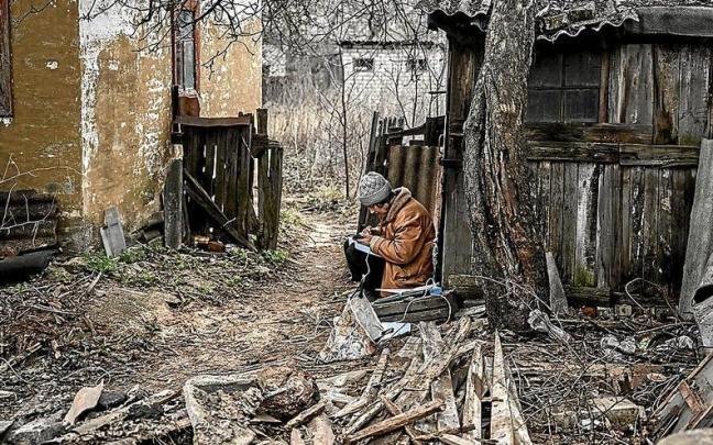 Una mujer usa su teléfono móvil para tomar notas sentada entre lo que queda de su casa destruida por los ataques en Bajmut. Una mujer usa su teléfono móvil para tomar notas sentada entre lo que queda de su casa destruida por los ataques en Bajmut.
