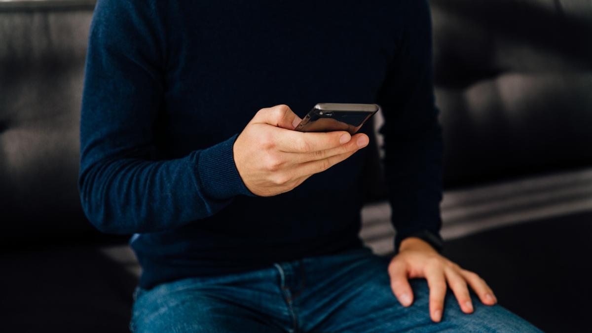 Un hombre consulta su teléfono móvil.