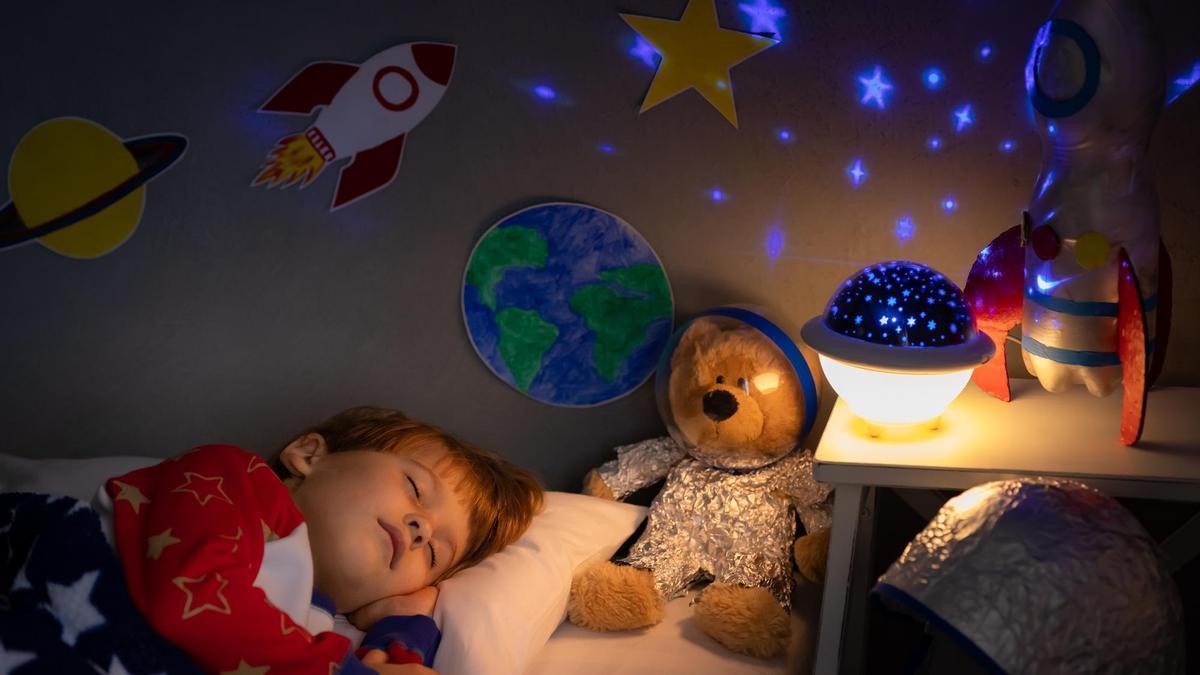 Un niño duerme con una luz nocturna sobre la mesa.