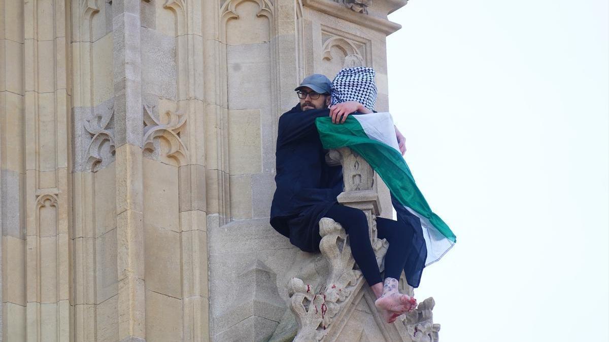 El hombre encaramado a la torre Elizabeth del palacio de Westminster, que alberga el Big Ben, con una bandera palestina.