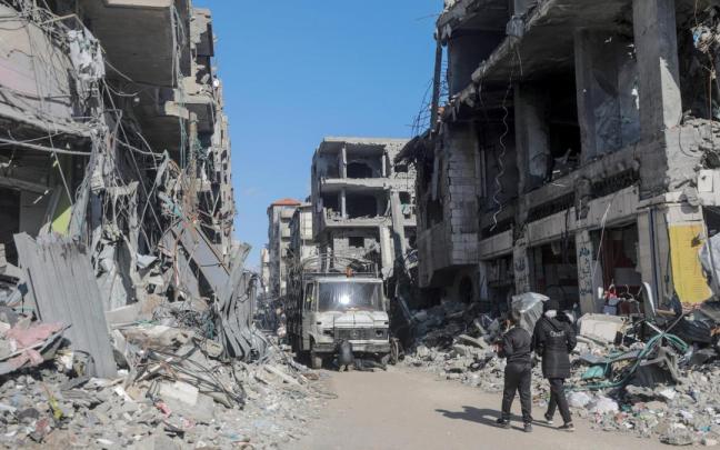 Dos palestinos pasean entre los edificios destruidos por la guerra en Al Nuseirat.