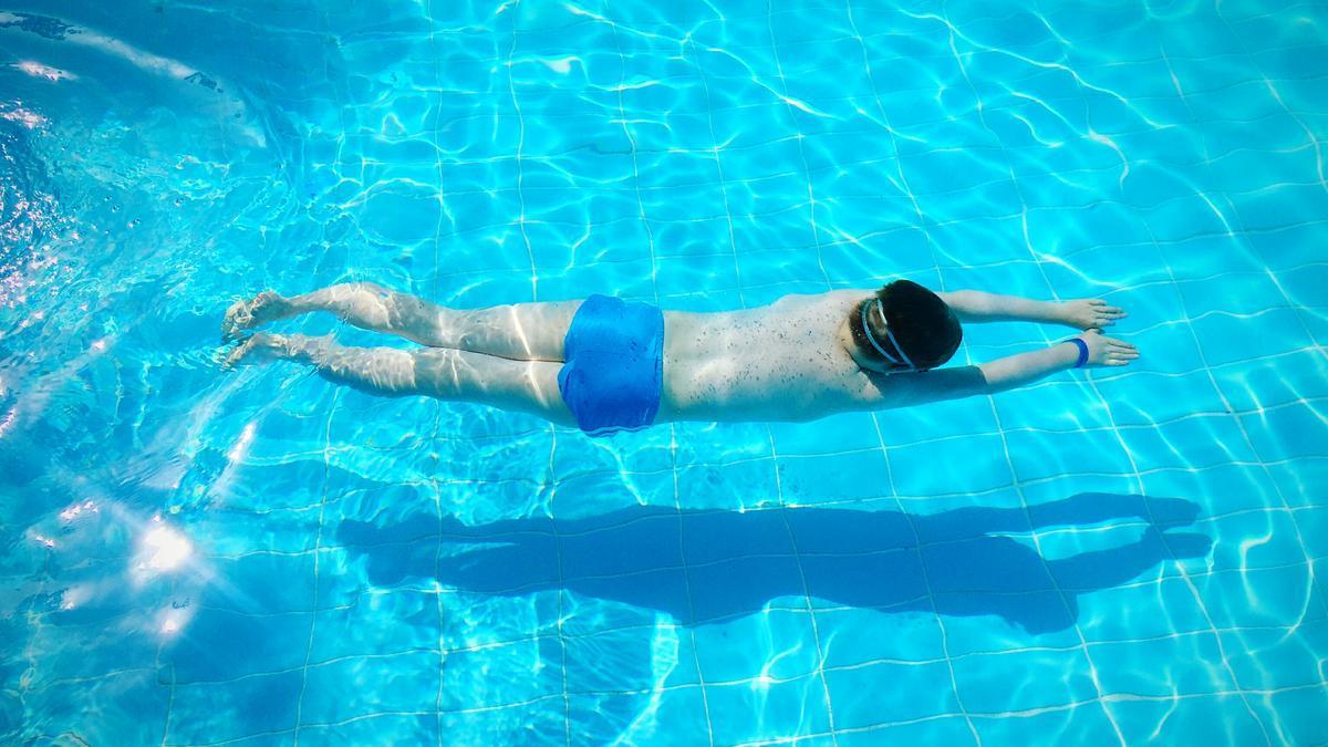 Un hombre bucea mientras practica natación en una piscina.