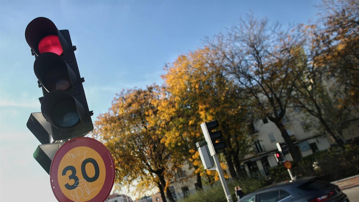 Varios coches circulan al lado de una señal de tráfico.