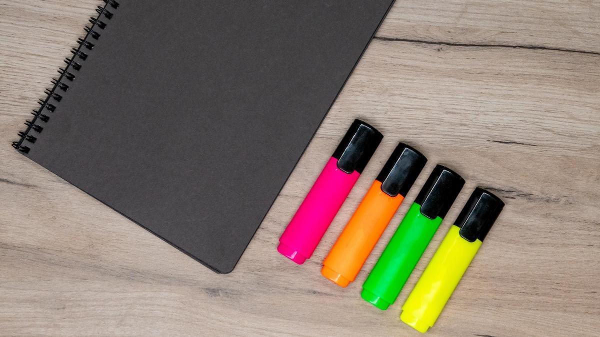 Subrayadores de colores junto a un cuaderno.