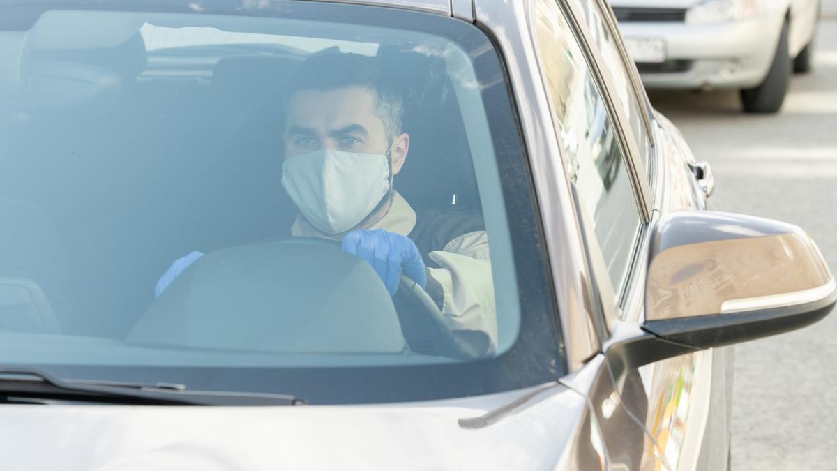 Un joven se tapa las vías respiratorias con una mascarilla y se protege las manos con unos guantes.