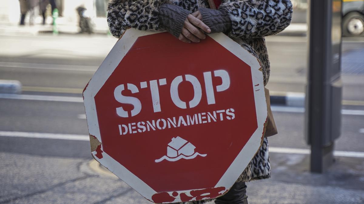 Una persona sujeta un cartel de 'Stop desnonamients' durante una concentración de la Plataforma de Afectados por la Hipoteca (PAH) para exigir una ley de derecho a la vivienda.