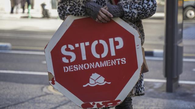 Una persona sujeta un cartel de 'Stop desnonamients' durante una concentración de la Plataforma de Afectados por la Hipoteca (PAH) para exigir una ley de derecho a la vivienda.