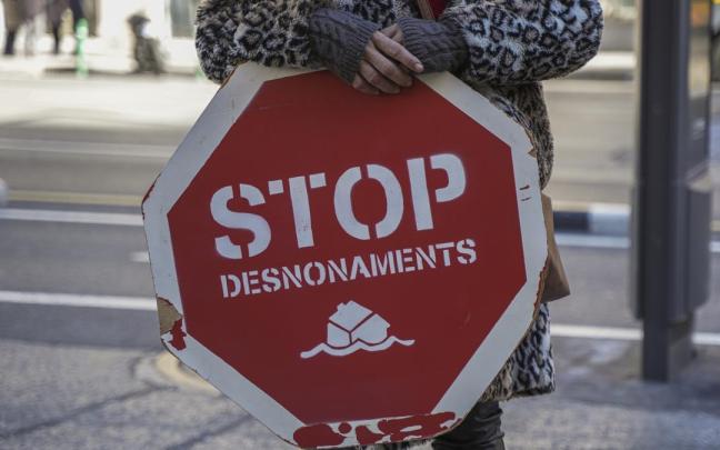 Una persona sujeta un cartel de 'Stop desnonamients' durante una concentración de la Plataforma de Afectados por la Hipoteca (PAH) para exigir una ley de derecho a la vivienda.