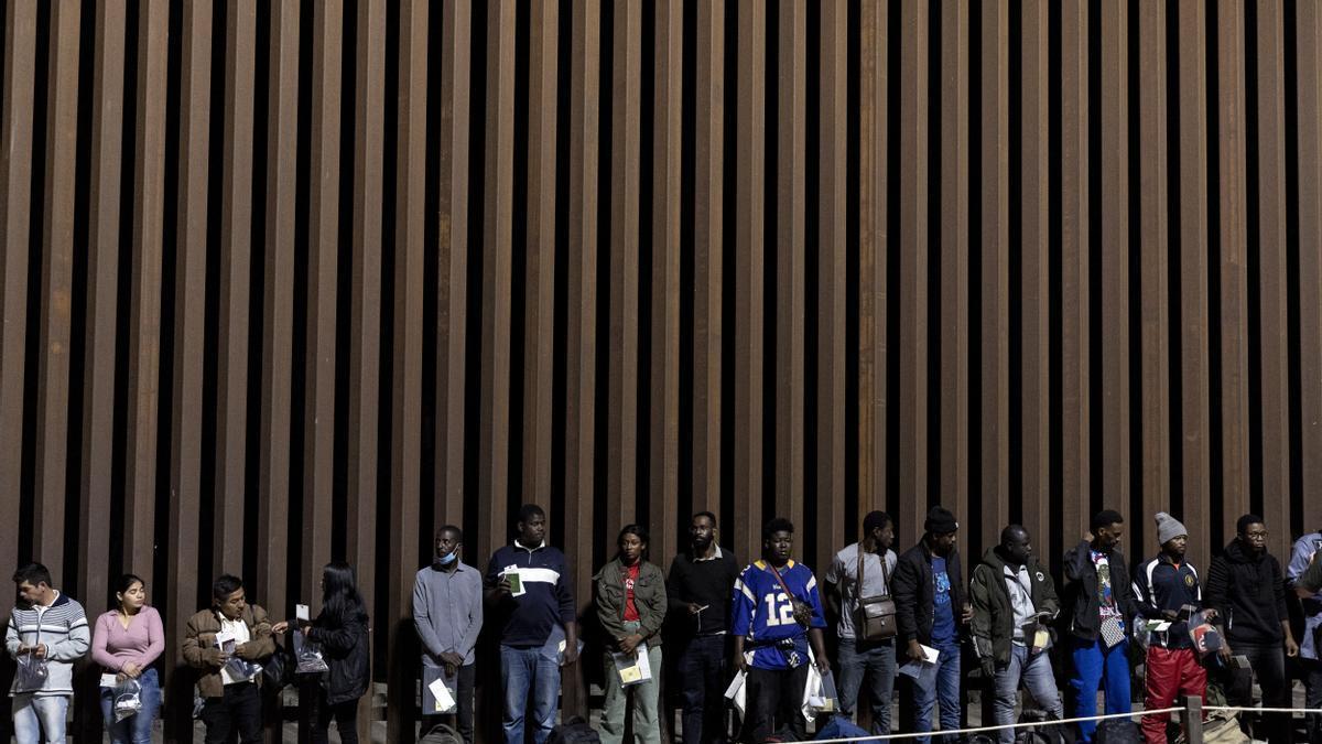 Un grupo de migrantes esperan en la frontera entre México y Estados Unidos en Yuma.