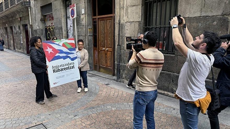 Dos personas portan el cartel de la campaña 'Argia eta indarra Kubarentzat. ¡Contra el bloqueo, energía para Cuba!'