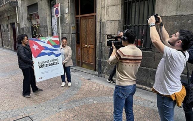 Dos personas portan el cartel de la campaña 'Argia eta indarra Kubarentzat. ¡Contra el bloqueo, energía para Cuba!'
