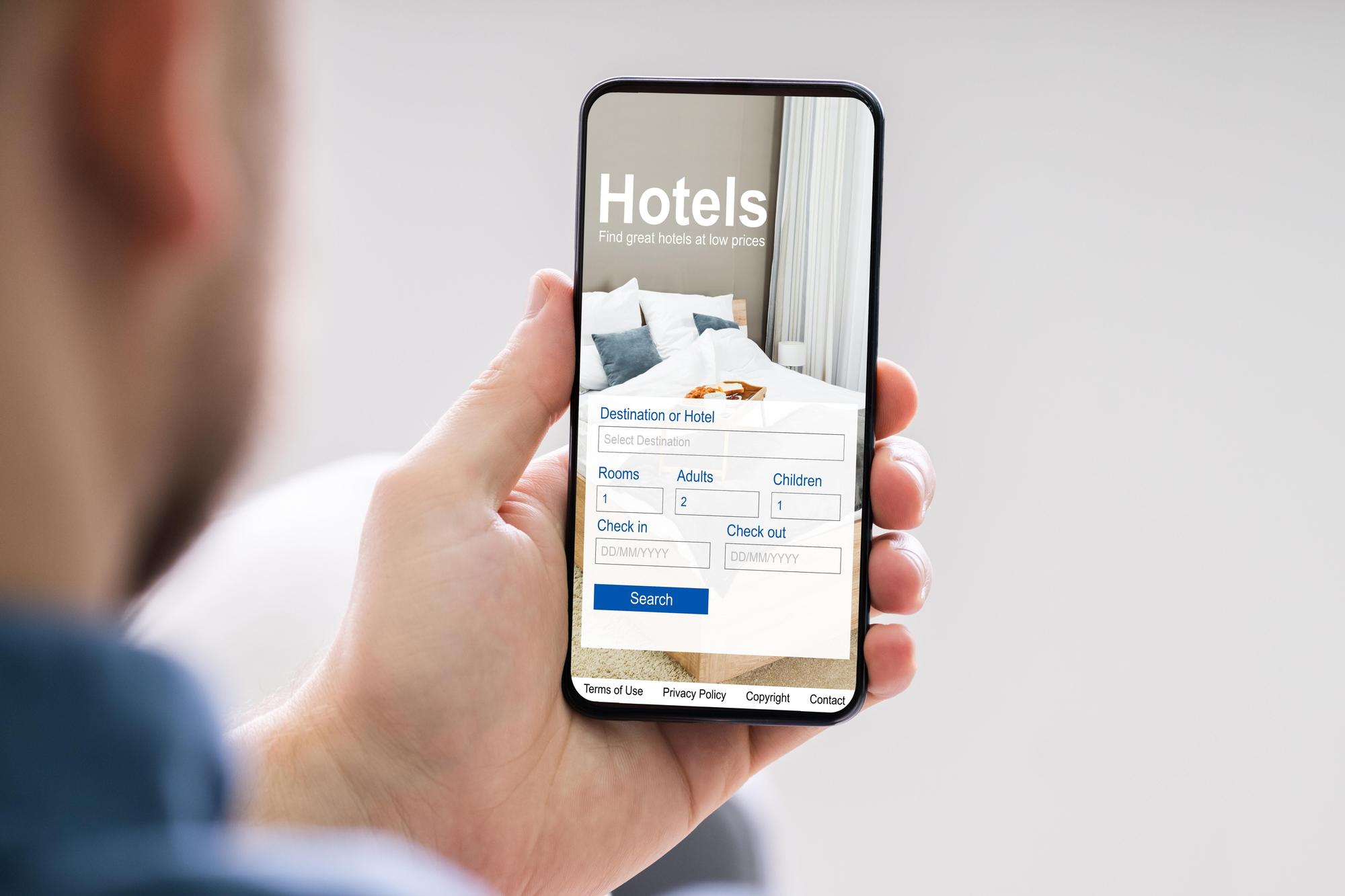 Un hombre busca en su teléfono móvil opciones de hotel para las vacaciones.
